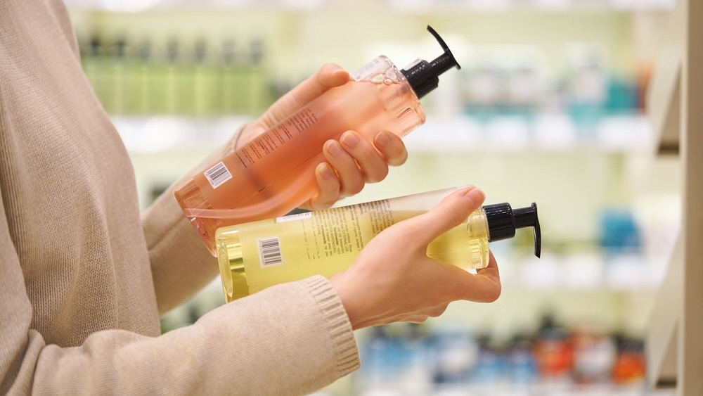 Person choosing between shampoo options, representing decision-making across drugstore, salon, and luxury products